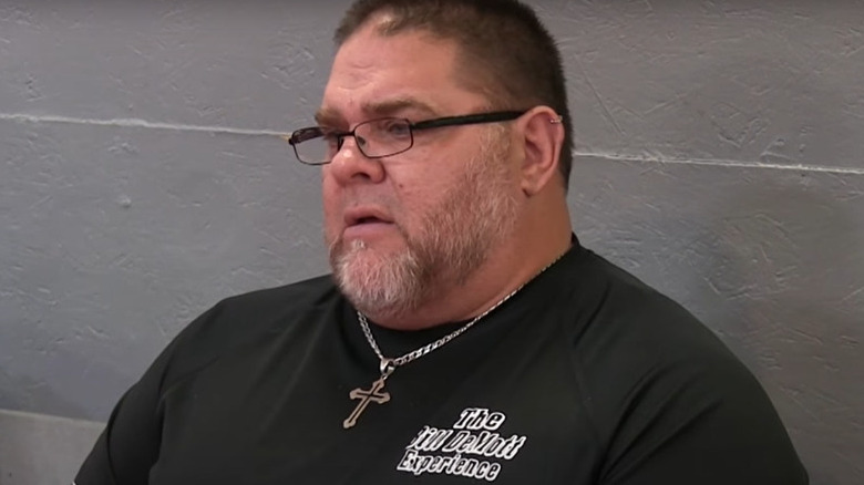Bill DeMott sitting cross necklace
