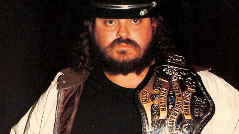 "Black Bart" Richard Harris poses with the NWA Heavyweight Championship while looking directly into the camera.