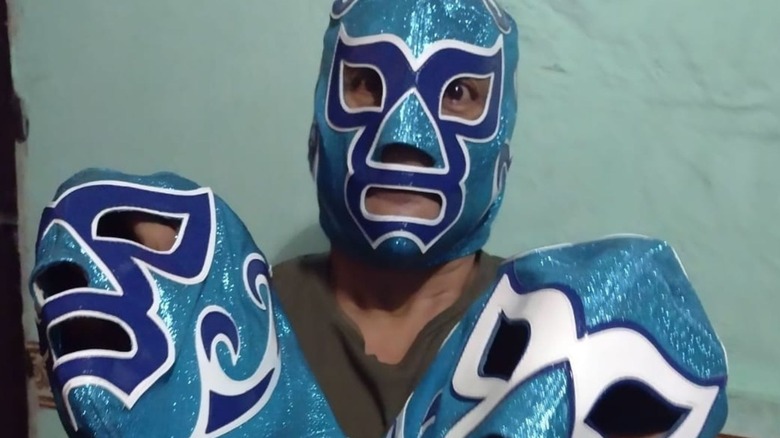 Ciclón Ramírez poses for a photo at home, showing off his masks he had for sale in an image posted to his Facebook page.