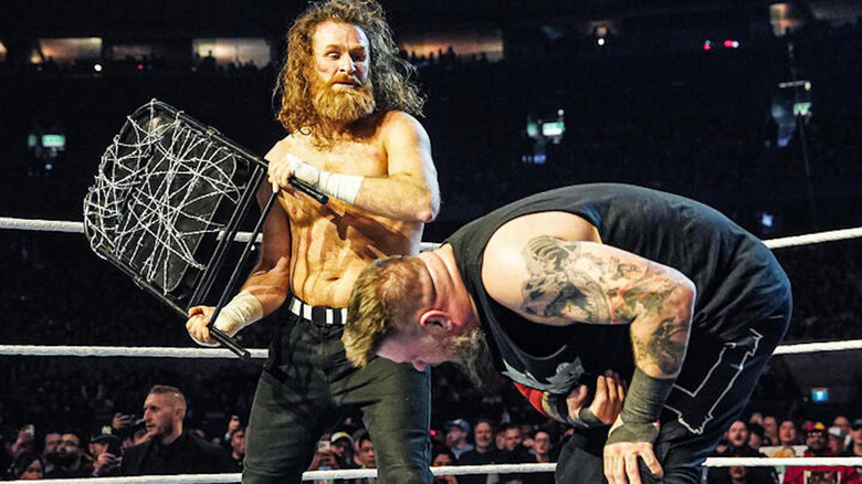 Sami Zayn prepares to hit Kevin Owens with chair wrapped in barbed wire at WWE Elimination Chamber
