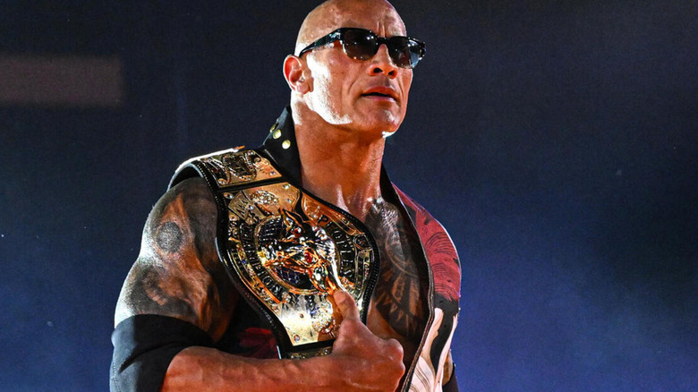 The Rock holds The People's Championship as he is illuminated from the bottom-up.