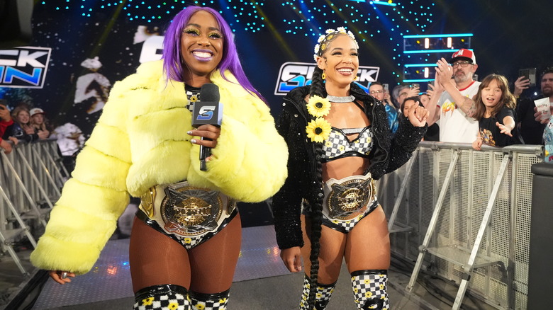 Naomi and Belair on the entrance ramp with their Women's Tag Team Championship belts