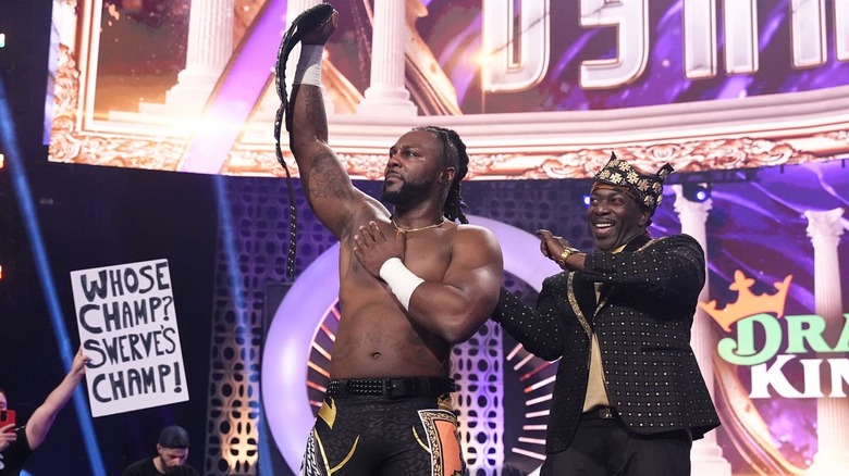 Swerve Strickland celebrates with the AEW world title after his main event win at AEW Dynasty 2024, Prince Nana dancing by his side