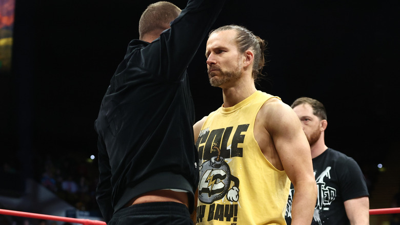 Daniel Garcia and Adam Cole stand face to face as Kyle O'Reilly watches.