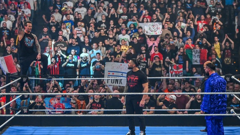 CM Punk holds the microphone high before laying a verbal assault on Roman Reigns and Seth Rollins