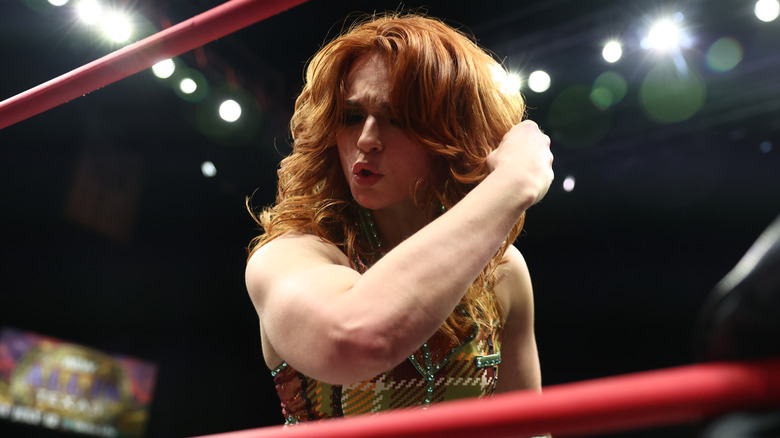Jamie Hayter kisses her bicep, the shot framed by red top and middle ropes.