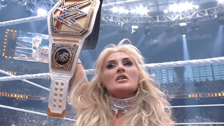 Tiffany Stratton holds up her WWE Women's Championship as she sports a chipped tooth.