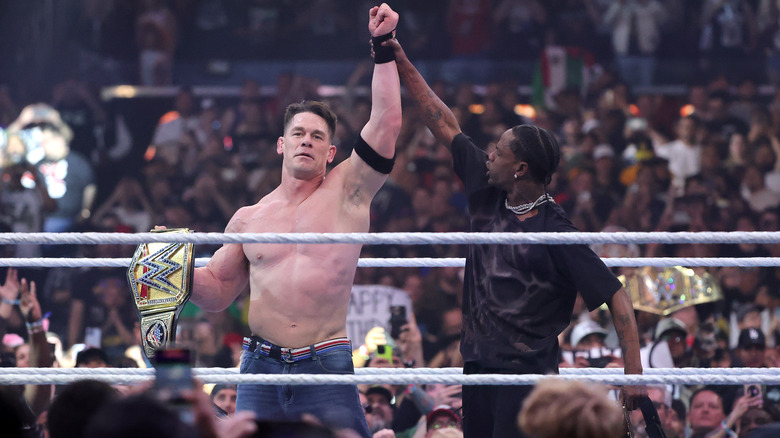 Travis Scott holds up John Cena's arm as he holds the WWE title at WrestleMania 41