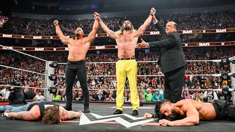 Seth Rollins and Bron Breakker raising their arms as Paul Heyman shows them off above a fallen Roman Reigns and CM Punk on "WWE Raw"