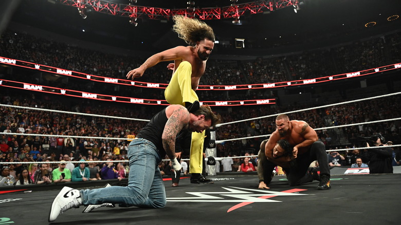 Seth Rollins stomps CM Punk as Bron Breakker holds Roman Reigns down