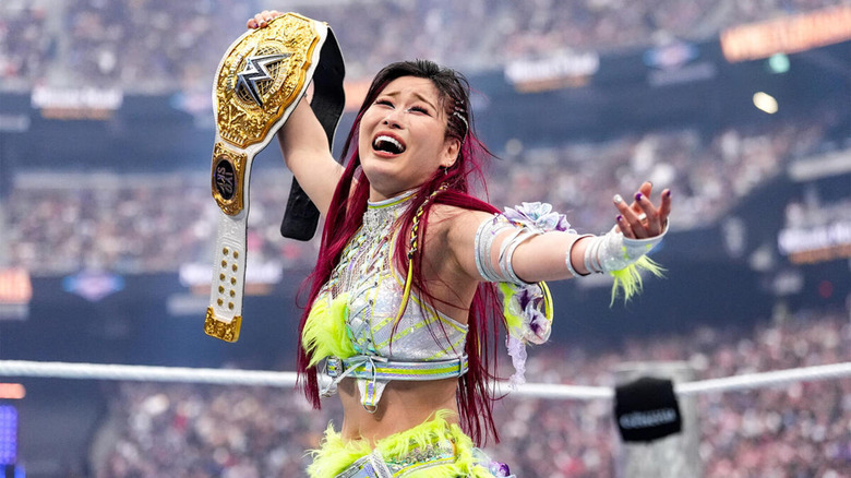 IYO SKY smiles in relief and disbelief as she holds her WWE Women's World Championship at WrestleMania.