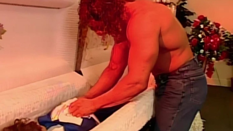 Triple H, wearing a Kane mask, stands over a mannequin in a coffin at a funeral home during a segment on "WWE Raw."