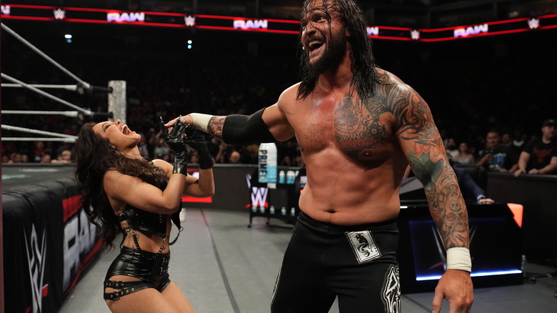 Karrion Kross holds Scarlett's hand as they both laugh outside the ring on "WWE Raw"