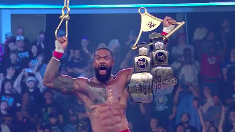 Montez Ford hoisting both tag titles in the air