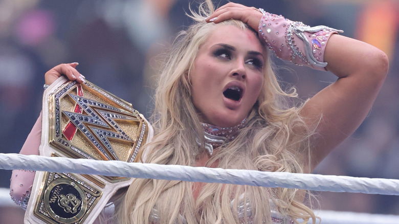 Tiffany Stratton holds up her WWE Women's Championship as she sports a chipped tooth.