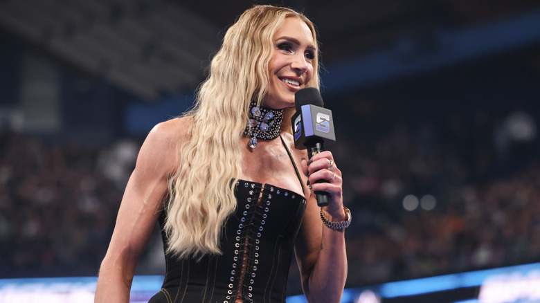 Charlotte Flair smiling and holding a microphone