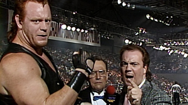 Mean Mark Callous flexing while Paul E. Dangerously cuts a promo