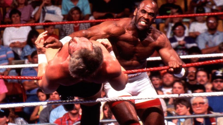 Former WWE star Virgil knocks a competitor over the top rope during a match.